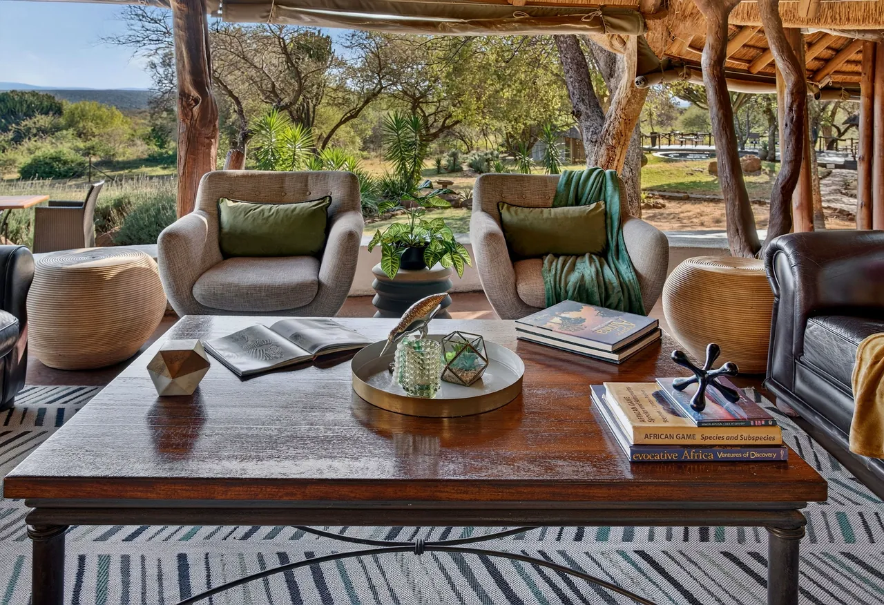 Armchairs and a coffee table with books, the bushveld beyond