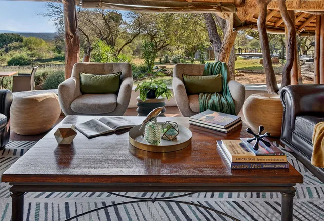 Armchairs and a coffee table with books, the bushveld beyond