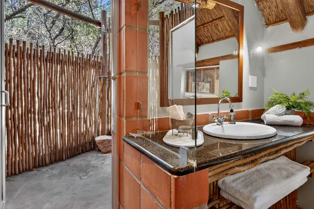 Bathroom vanity with a round basin beside the screened outdoor shower