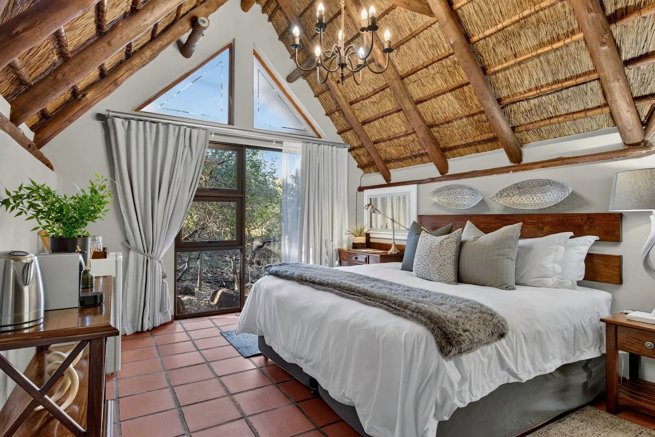 Bedroom with a high thatched ceiling, chandelier and canopy curtains