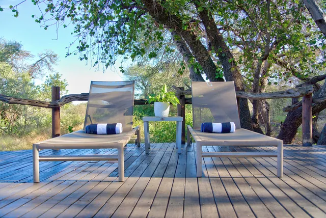 Two sun loungers with striped towels on a shaded timber deck
