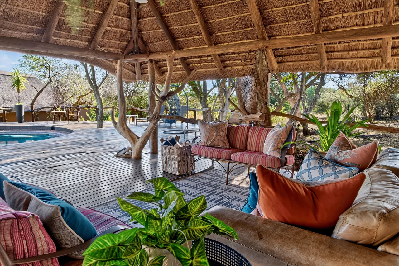 Open-air lounge with deep sofas and cushions beside the pool deck