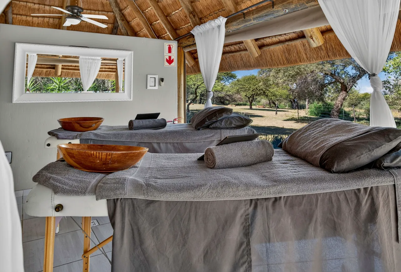 Two treatment beds with rolled towels in an open-air thatched spa