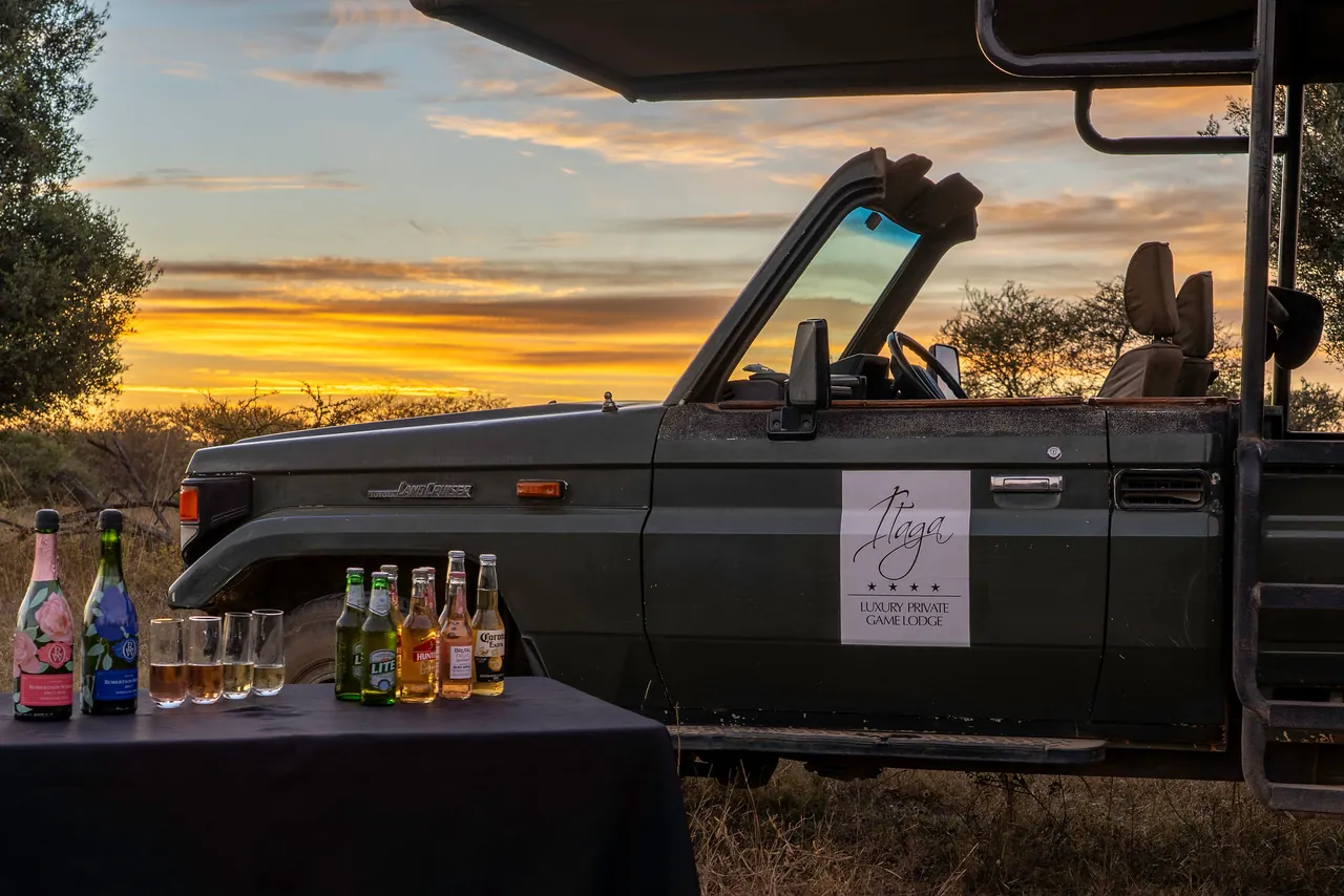 Sundowner drinks set out beside a safari vehicle at sunset