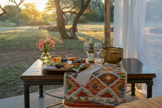 Table set with snacks and wine glasses on the lawn at sunset