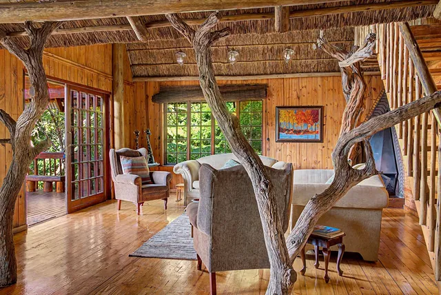 Timber-clad lounge with armchairs, a sofa and french doors
